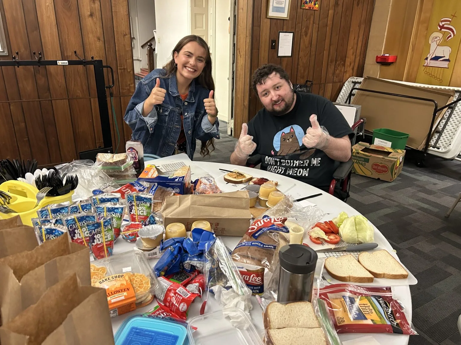 Two people with disabilities giving thumbs up at a snack table