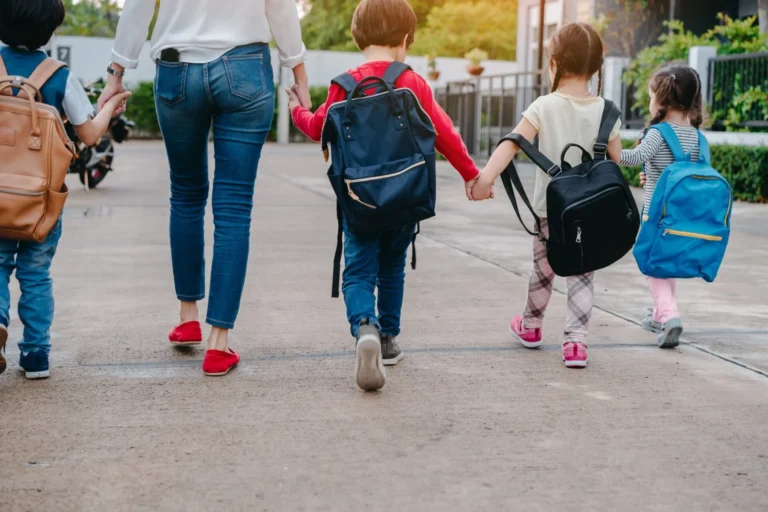 Back to School of Mother and pupil and kids holding hands going